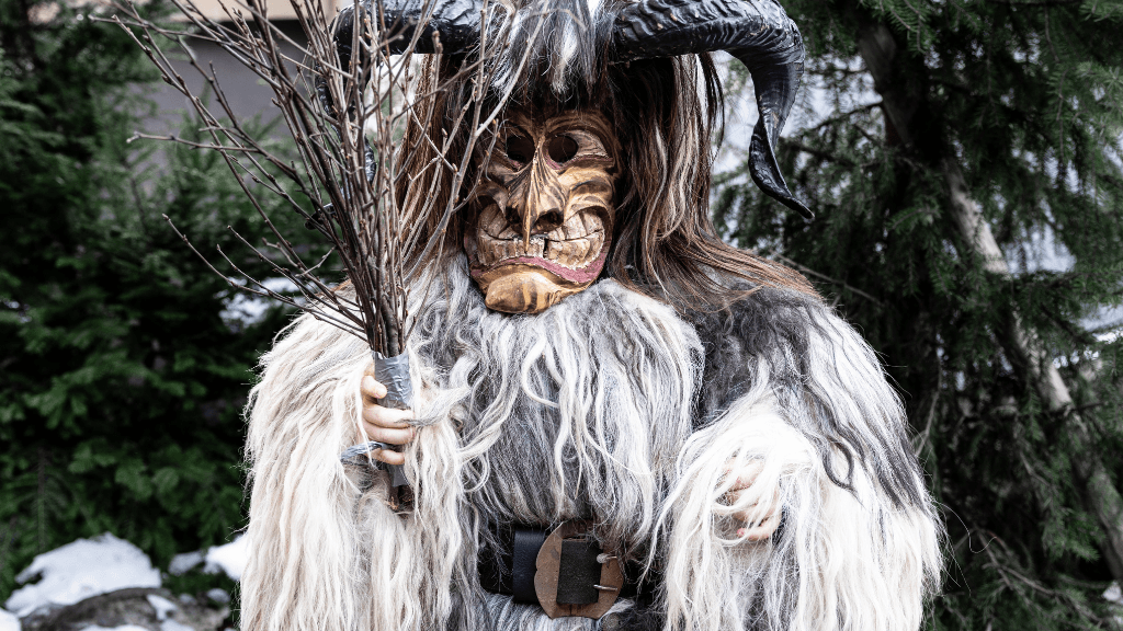 A scary-looking horned figure holding a cluster of birch rods for punishing naughty children.